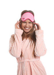 Young woman in bathrobe with sleep mask on white background