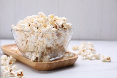 Photo of Bowl of tasty popcorn on white table, closeup. Space for text