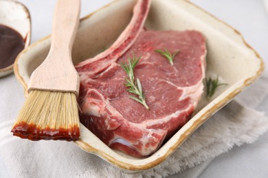 Photo of Raw meat, rosemary and brush with marinade on light table, closeup