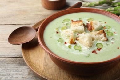 Photo of Delicious asparagus soup with croutons served on wooden table, closeup