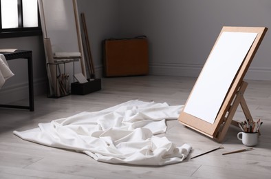Photo of Stylish artist's studio interior with canvas, white fabric and brushes