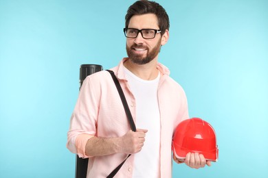 Photo of Architect with drawing tube and hard hat on light blue background