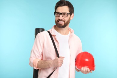 Architect with drawing tube and hard hat on light blue background