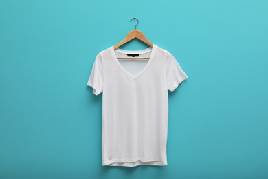 Photo of Hanger with blank t-shirt on color background. Mockup for design