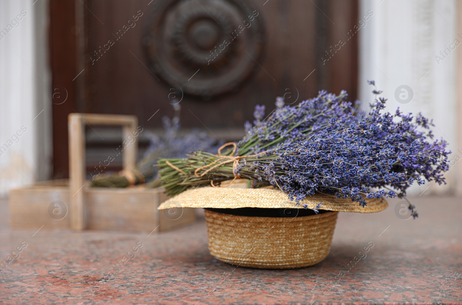 Photo of Beautiful lavender flowers and straw hat near building outdoors