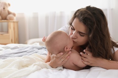 Photo of Happy young mother with her cute baby on bed at home