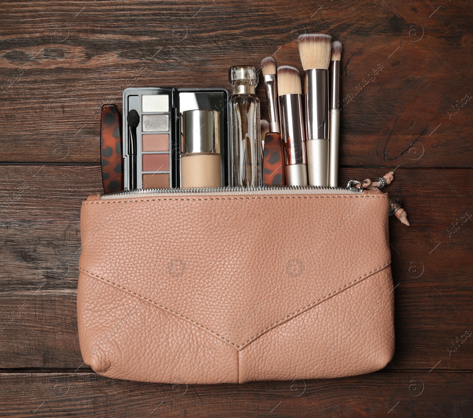 Photo of Cosmetic bag with makeup products and beauty accessories on wooden background, flat lay