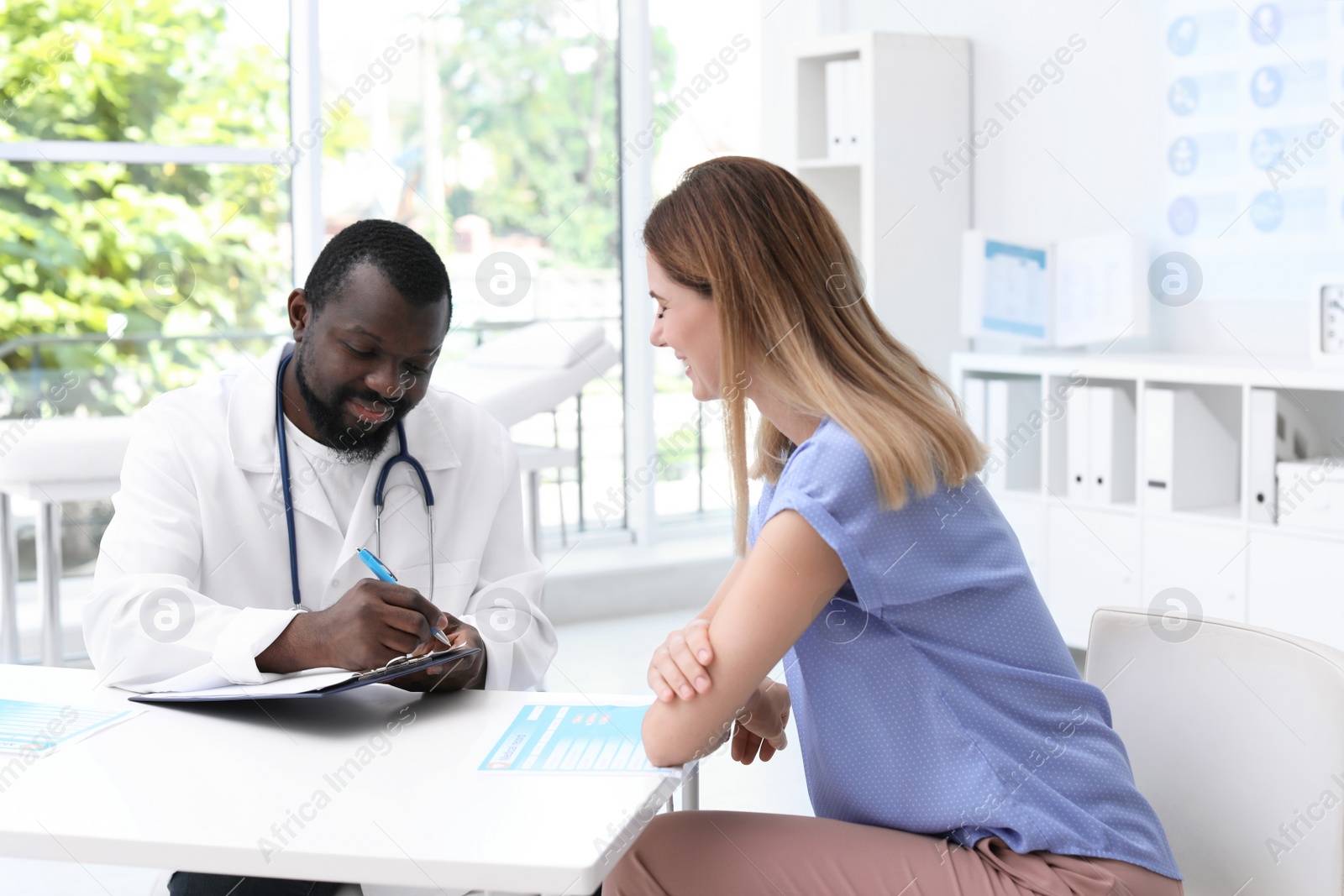 Photo of Young African-American doctor speaking with his patient in hospital