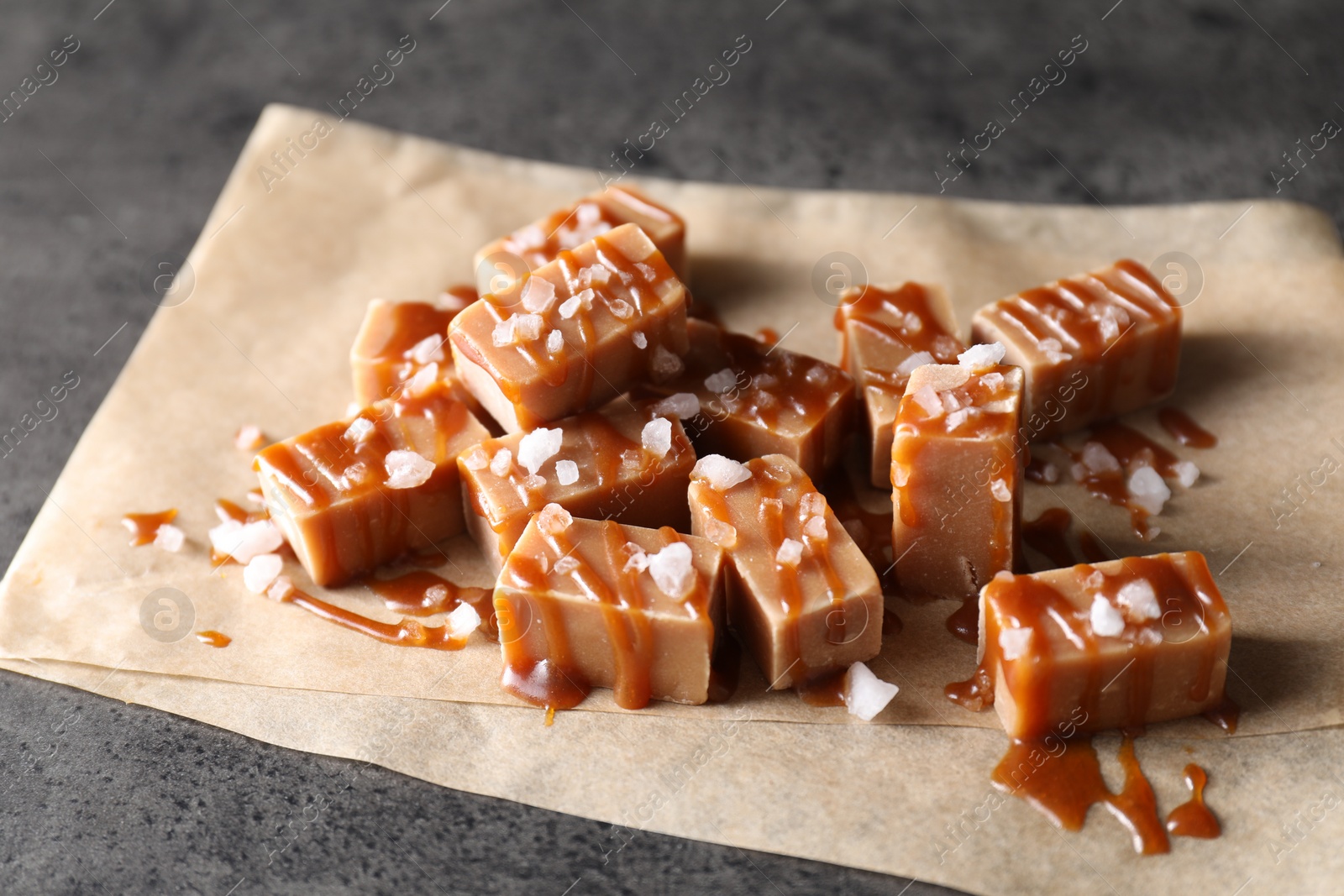 Photo of Tasty candies, caramel sauce and salt on grey table, closeup