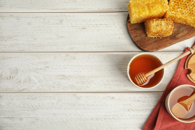 Flat lay composition with delicious honey on white wooden table. Space for text