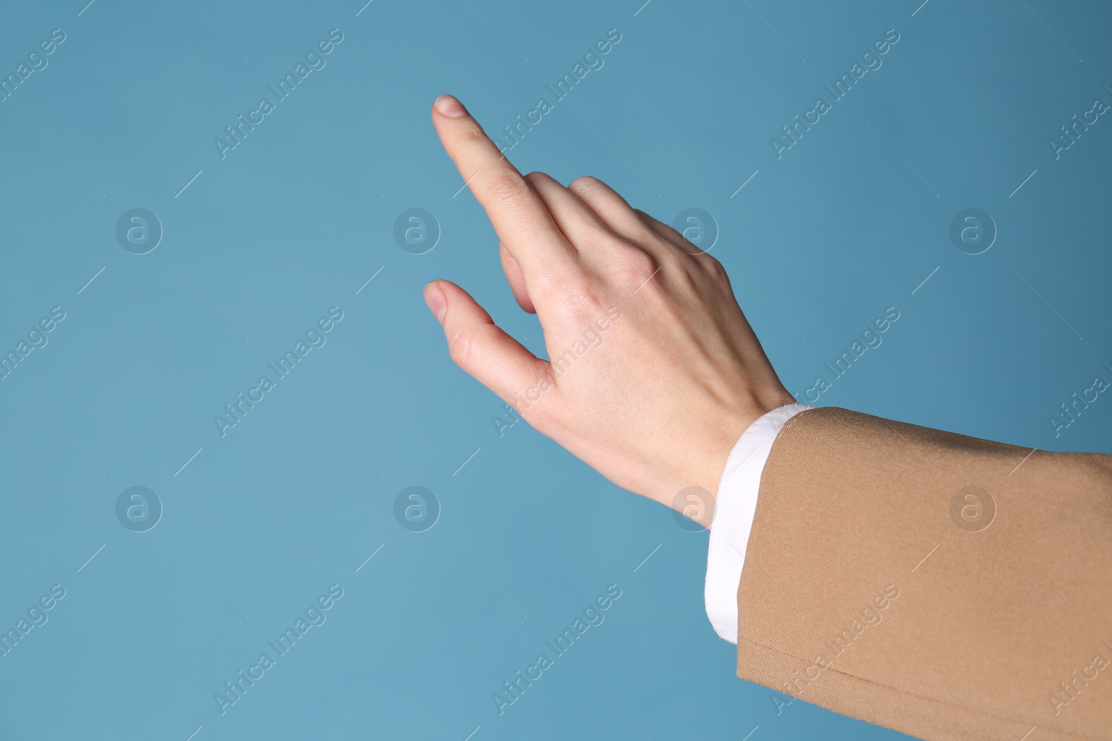 Photo of Businesswoman pointing at something on light blue background, closeup. Finger gesture