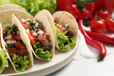 Photo of Delicious tacos with meat and vegetables on white table, closeup