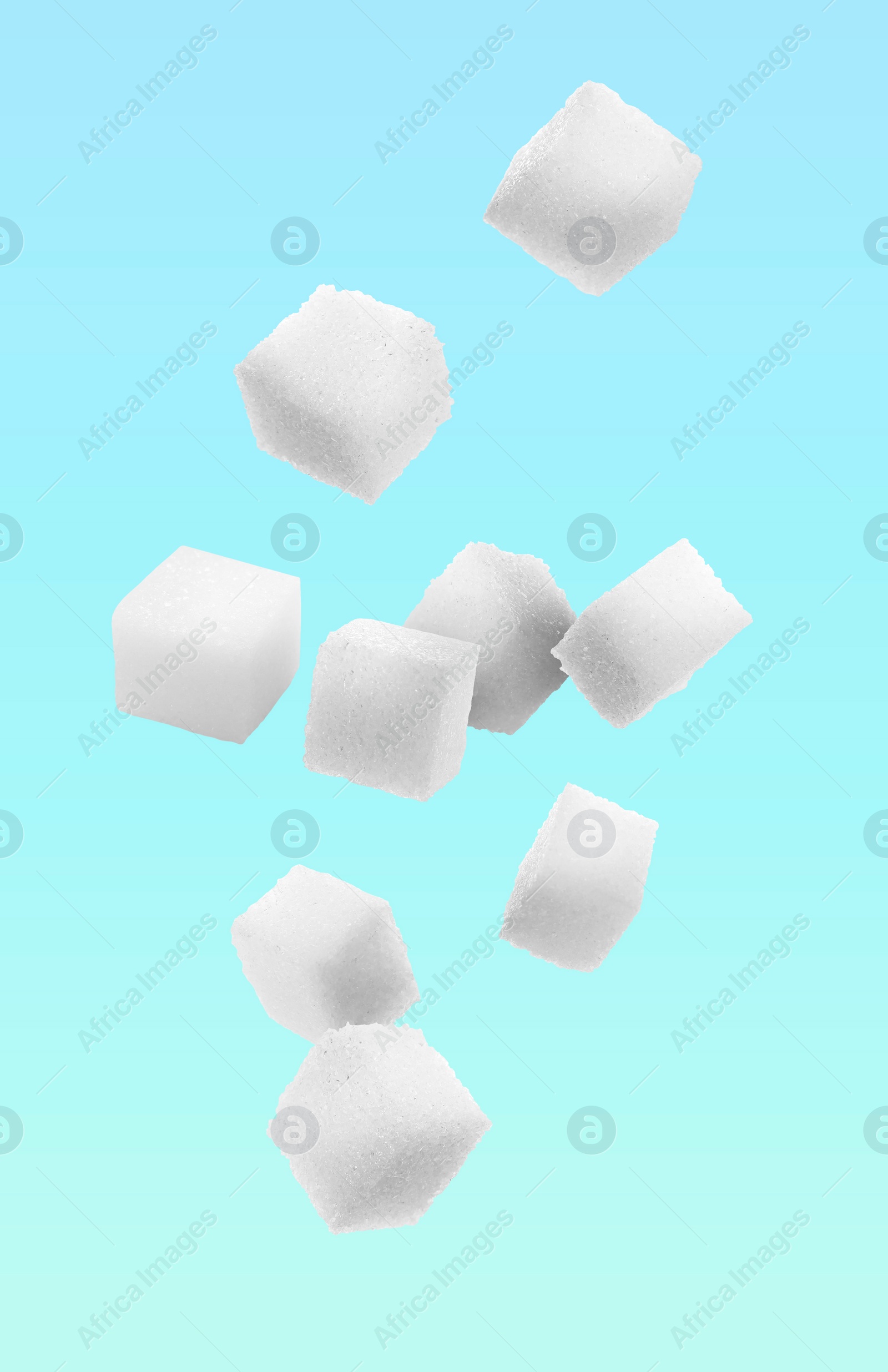 Image of Refined sugar cubes in air on light blue background