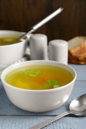 Delicious chicken bouillon with parsley on grey wooden table