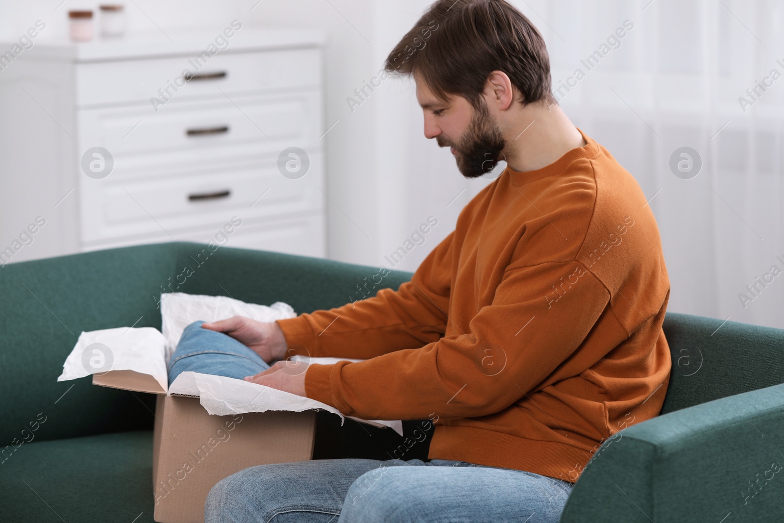 Photo of Man opening parcel at home. Internet shopping
