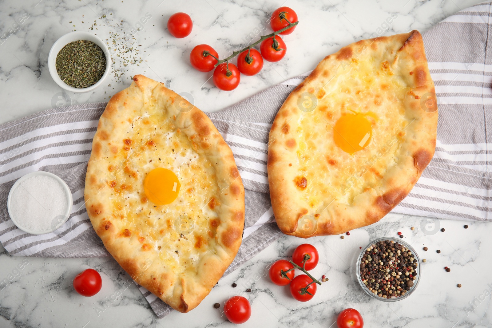 Photo of Fresh delicious Adjarian khachapuris served on white marble table, flat lay