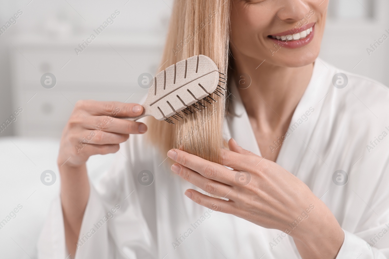 Photo of Woman brushing her hair indoors, closeup view