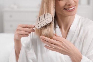 Photo of Woman brushing her hair indoors, closeup view