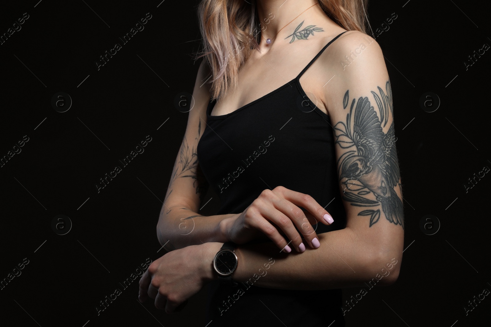 Photo of Beautiful woman with tattoos on body against black background, closeup