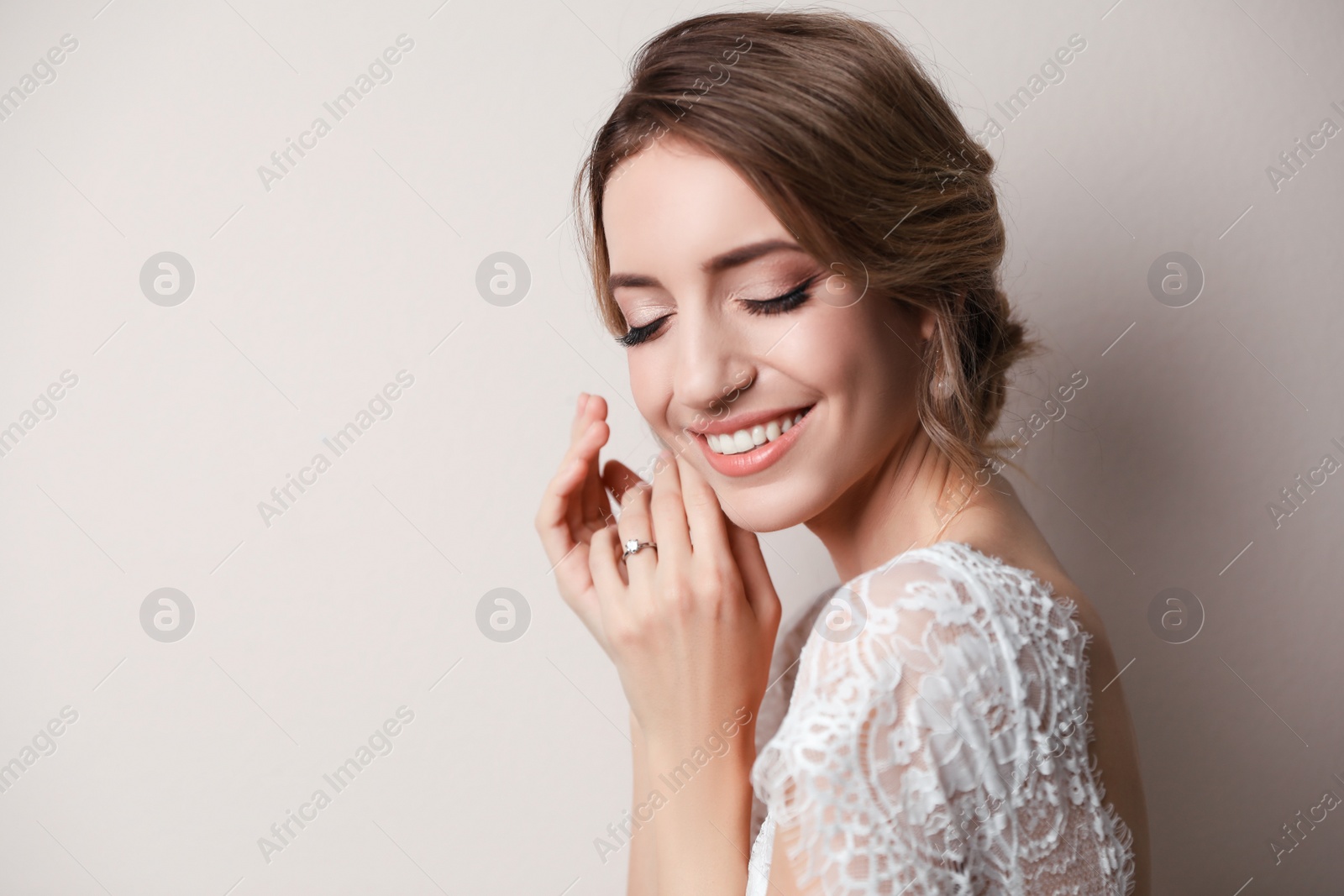 Photo of Young bride with elegant wedding hairstyle on beige background. Space for text
