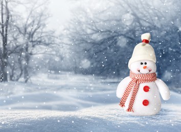 Image of Cute decorative snowman in hat and scarf outdoors on snowy day, space for text