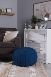 Stylish knitted pouf and chest of drawers in room. Home design