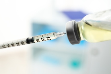 Filling syringe with vaccine on blurred background, closeup