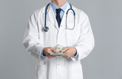 Doctor with bribe on grey background, closeup. Corruption in medicine