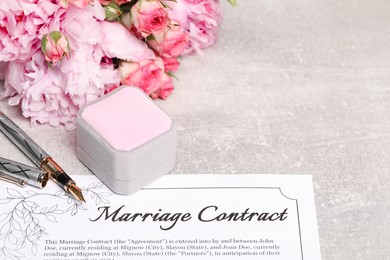 Marriage contract, fountain pen, jewelry box and flowers on grey table