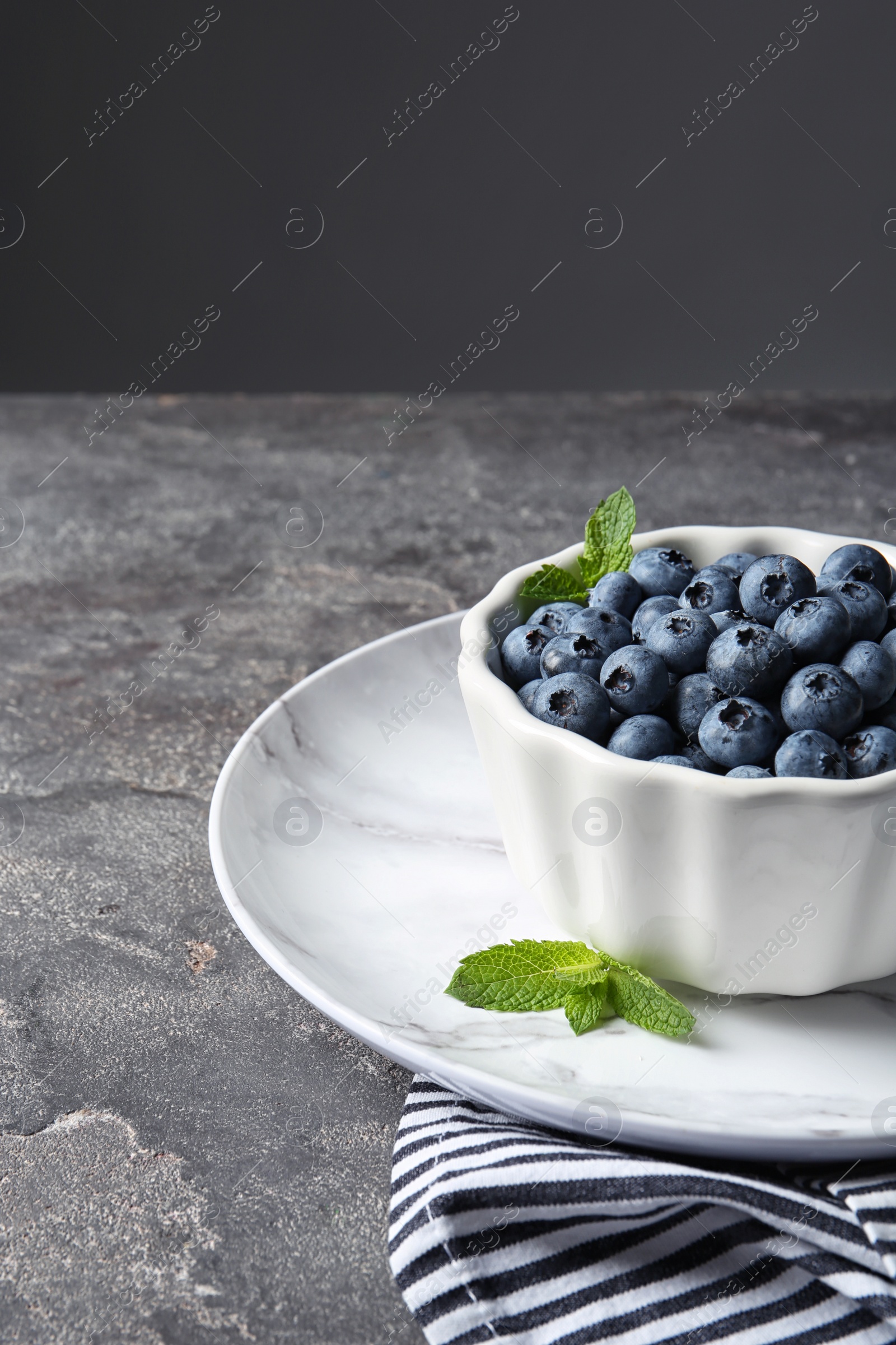 Photo of Crockery with juicy blueberries on color table