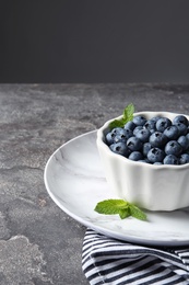 Photo of Crockery with juicy blueberries on color table