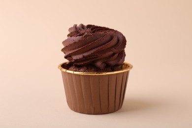 Photo of Delicious chocolate cupcake on beige background, closeup