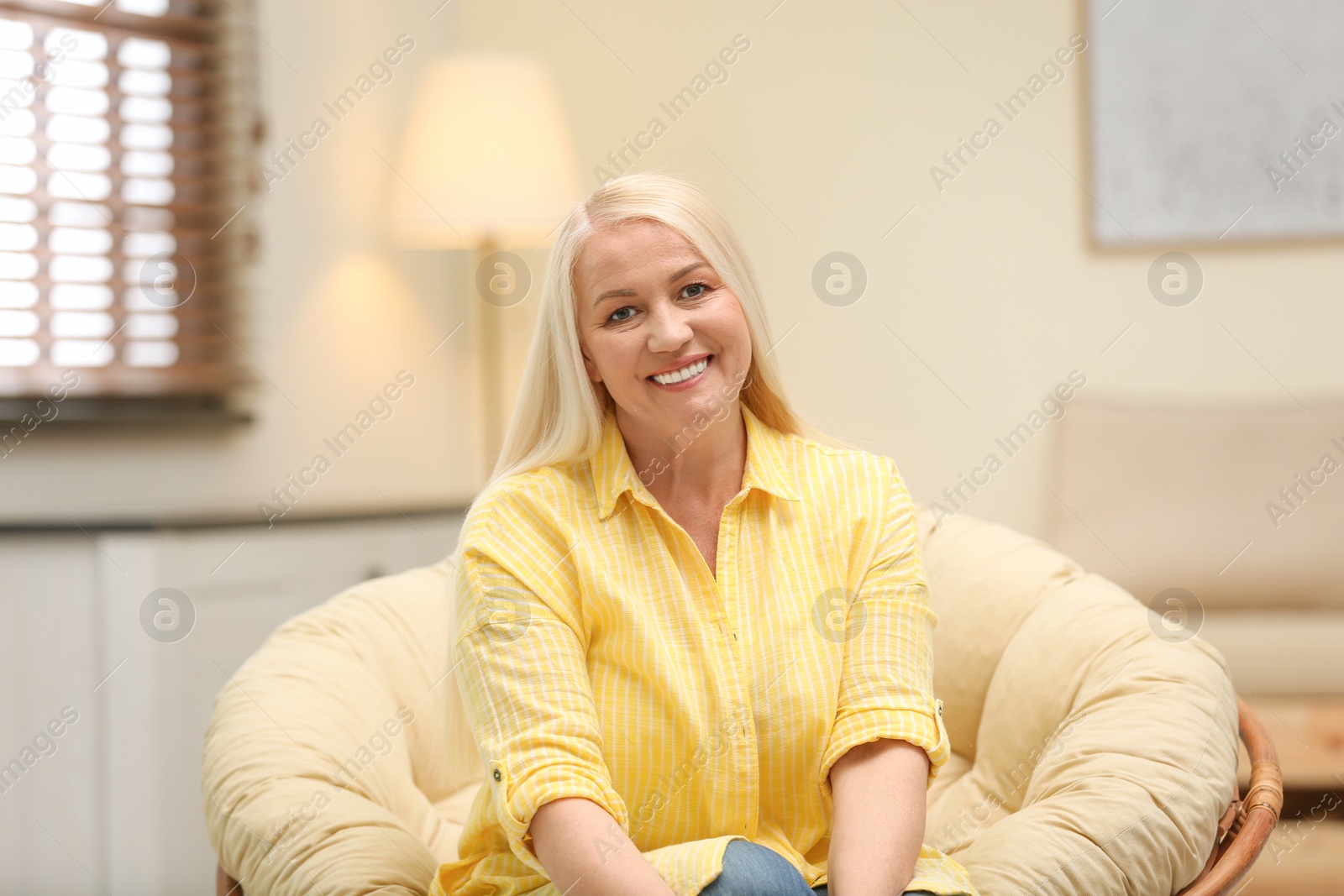 Photo of Portrait of happy mature woman sitting in papasan chair at home