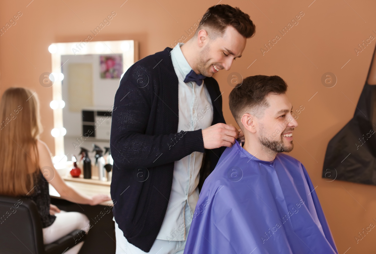 Photo of Professional hairdresser working with client in beauty salon