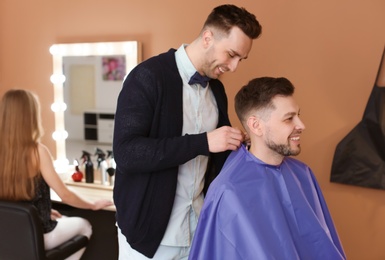 Photo of Professional hairdresser working with client in beauty salon