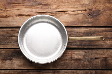 New metal frying pan on wooden table, top view