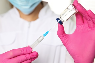 Doctor with vial and syringe in hospital, closeup. Vaccination day