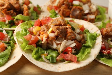 Photo of Delicious tacos with vegetables and meat on table, closeup