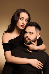 Photo of Handsome bearded man with sexy lady on light brown background