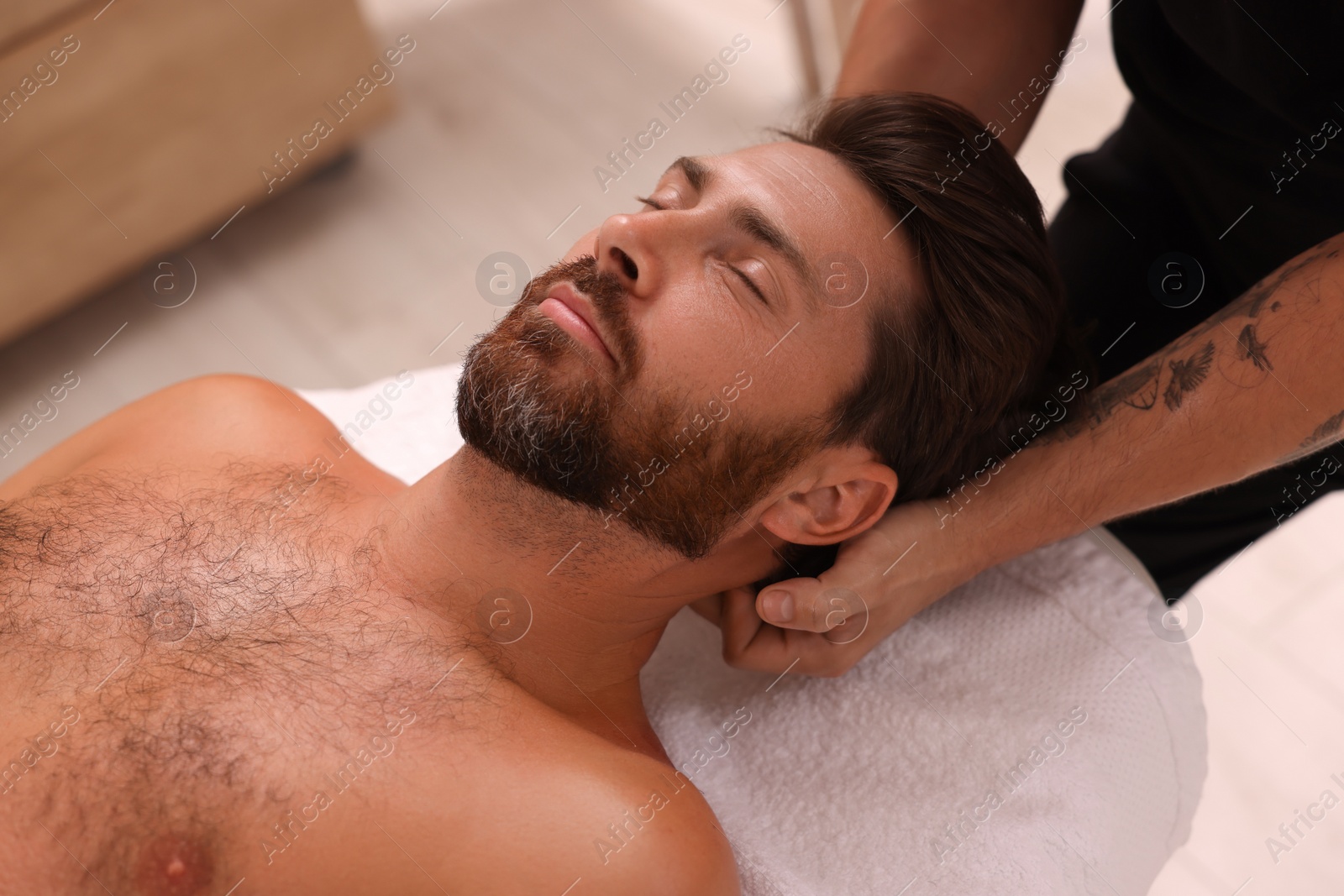 Photo of Man receiving professional neck massage in spa salon