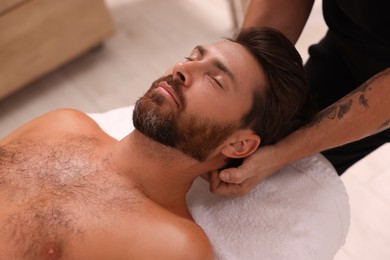 Photo of Man receiving professional neck massage in spa salon