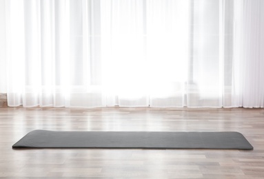 Photo of Grey yoga mat on floor indoors. Space for text