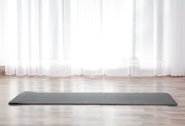 Grey yoga mat on floor indoors. Space for text