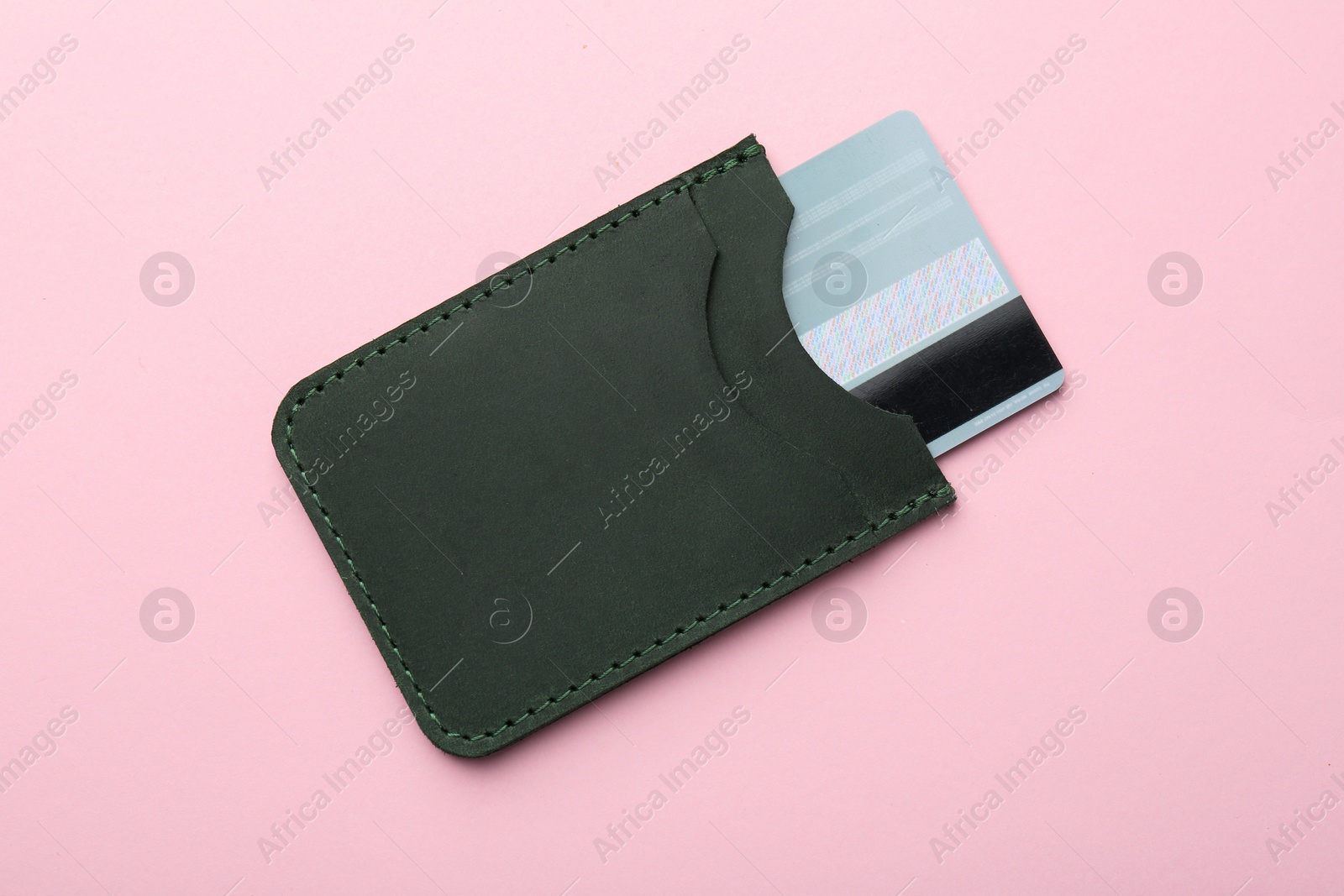 Photo of Leather card holder with credit card on pink background, top view