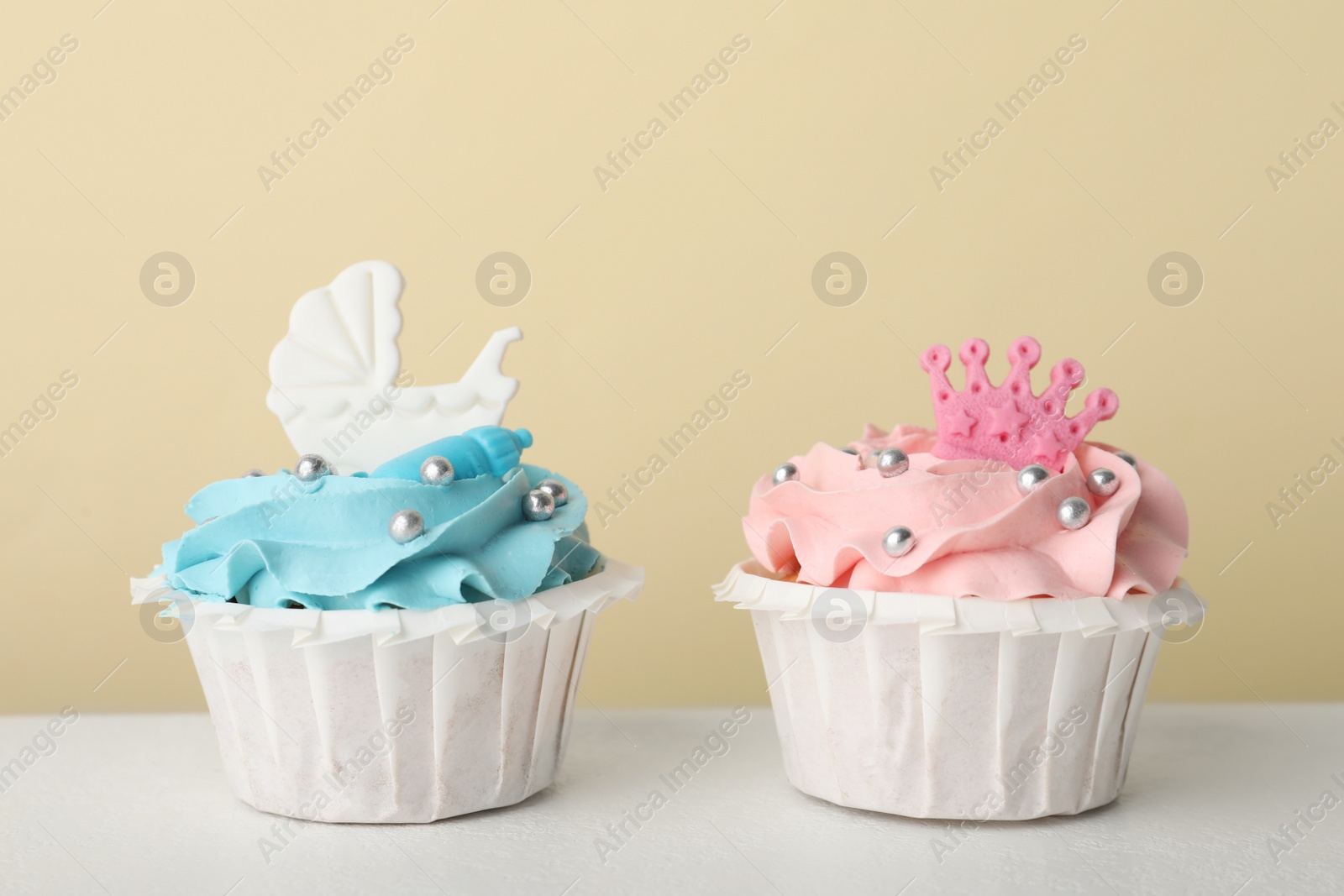 Photo of Delicious cupcakes with pink and light blue cream for baby shower on white table