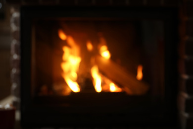 Blurred view of fireplace with burning wood indoors