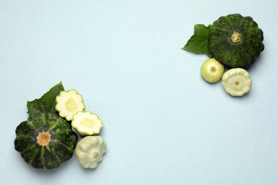 Fresh ripe pattypan squashes with leaves on light background, flat lay. Space for text