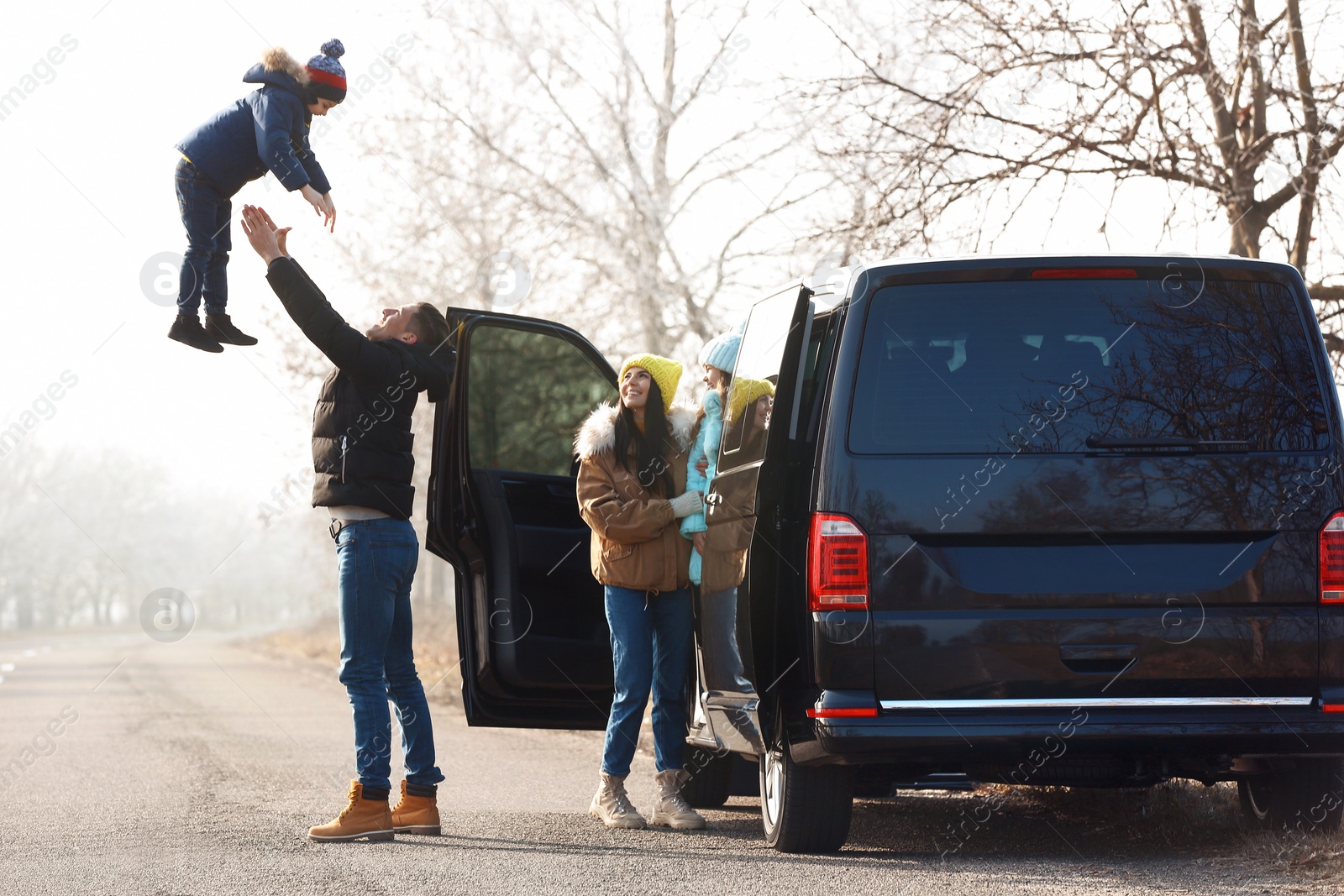 Photo of Happy family with little children near modern car on road