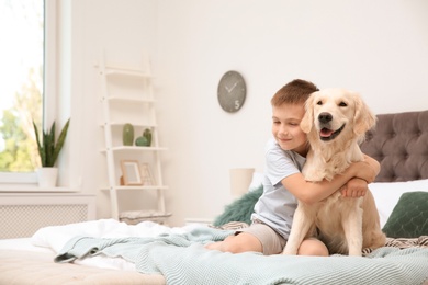 Photo of Cute little child with his pet on bed at home