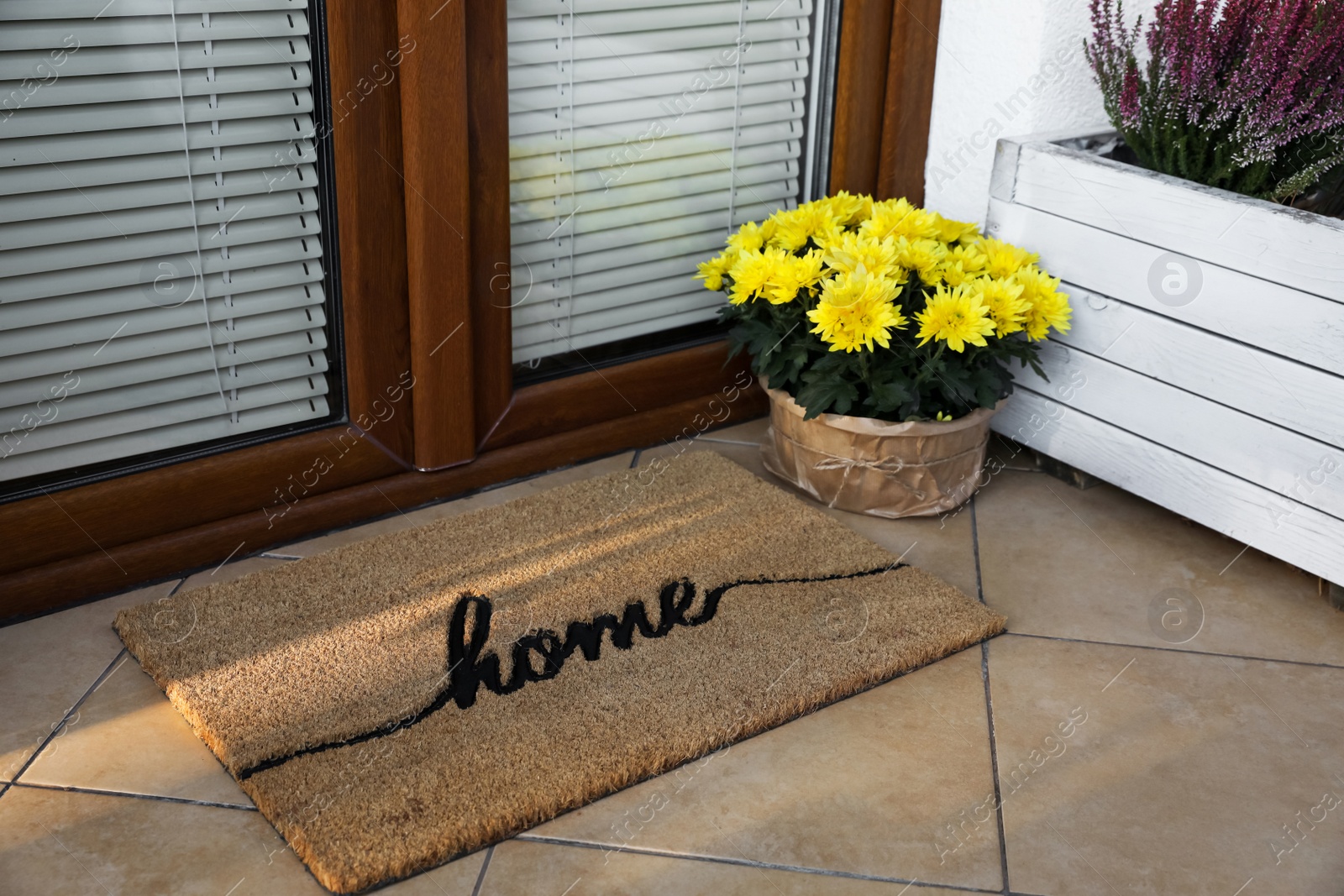 Photo of Doormat with word Home and flowers near entrance outdoors